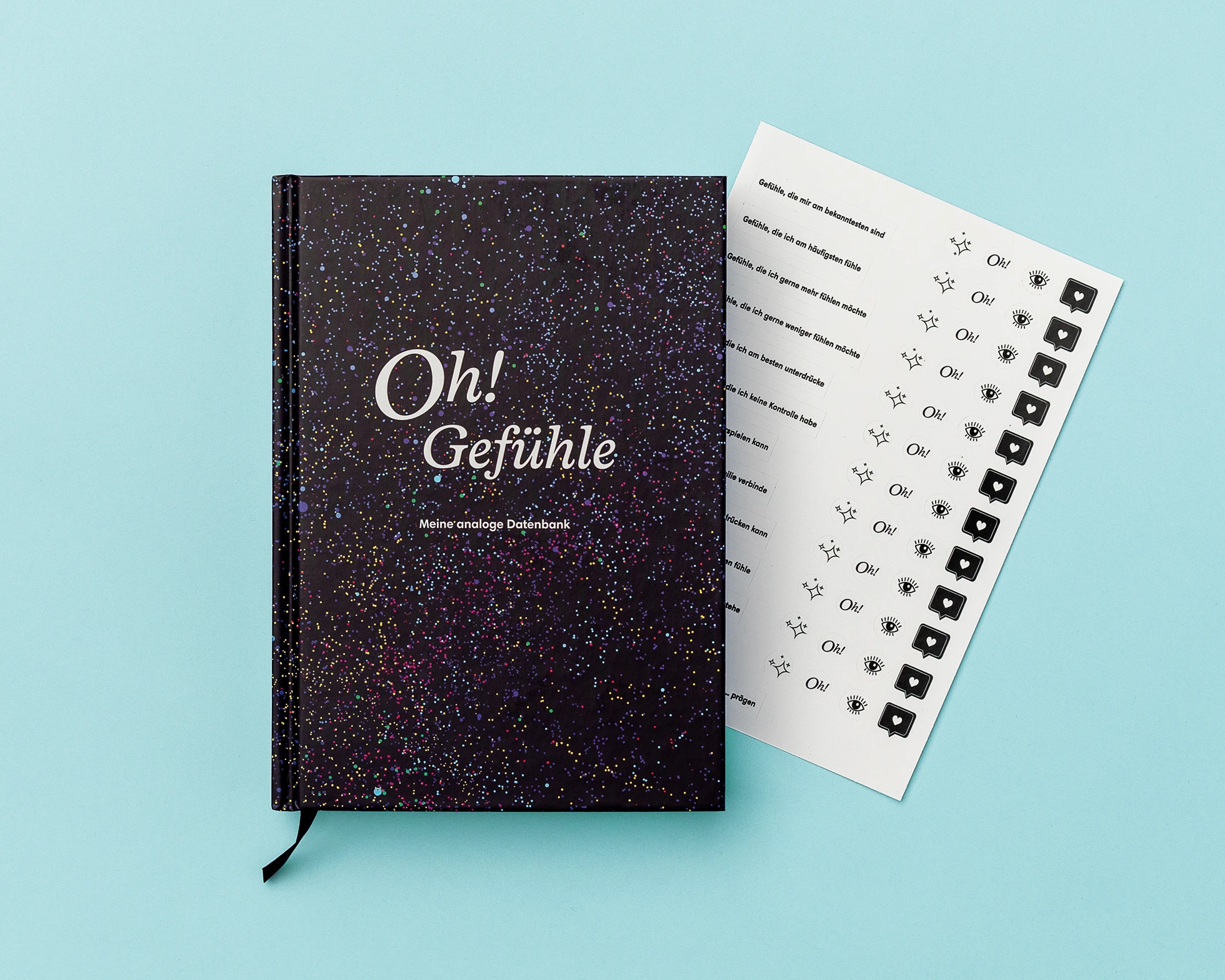 Das Buch Oh! Gefühle - Meine analoge Datenbank frontal, der Stickerbogen schaut auffällig heraus, auf türkisfarbenem Hintergrund.